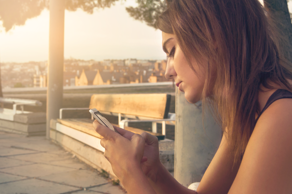 Mujer grabando un vídeo vertical con el móvil al aire libre, preparando una historia para Instagram