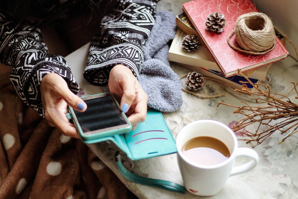 Mujer fotografiando con el móvil una taza de café sobre una mesa, pensando en qué publicar en Instagram