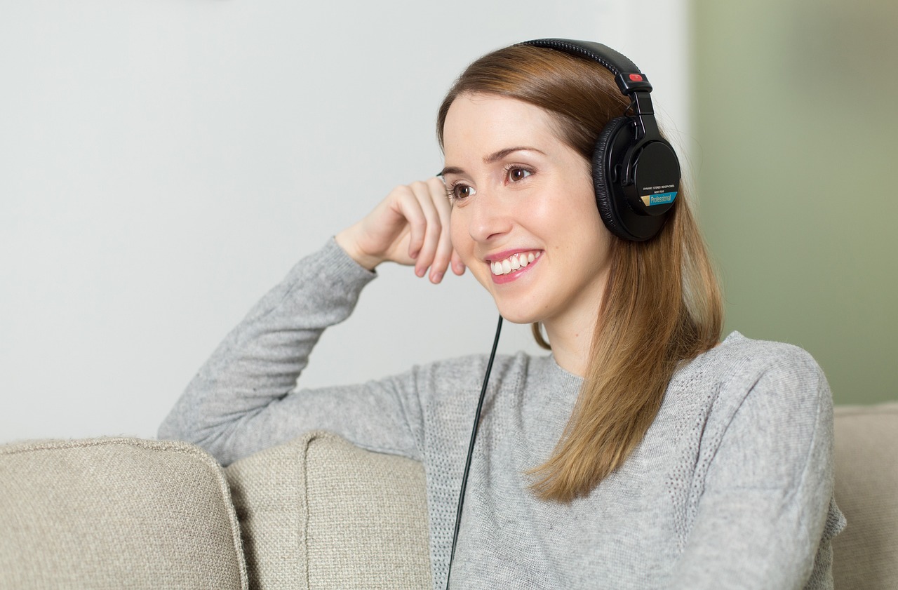 Joven escuchando música con auriculares mientras mira su móvil, comprobando el sonido de una canción