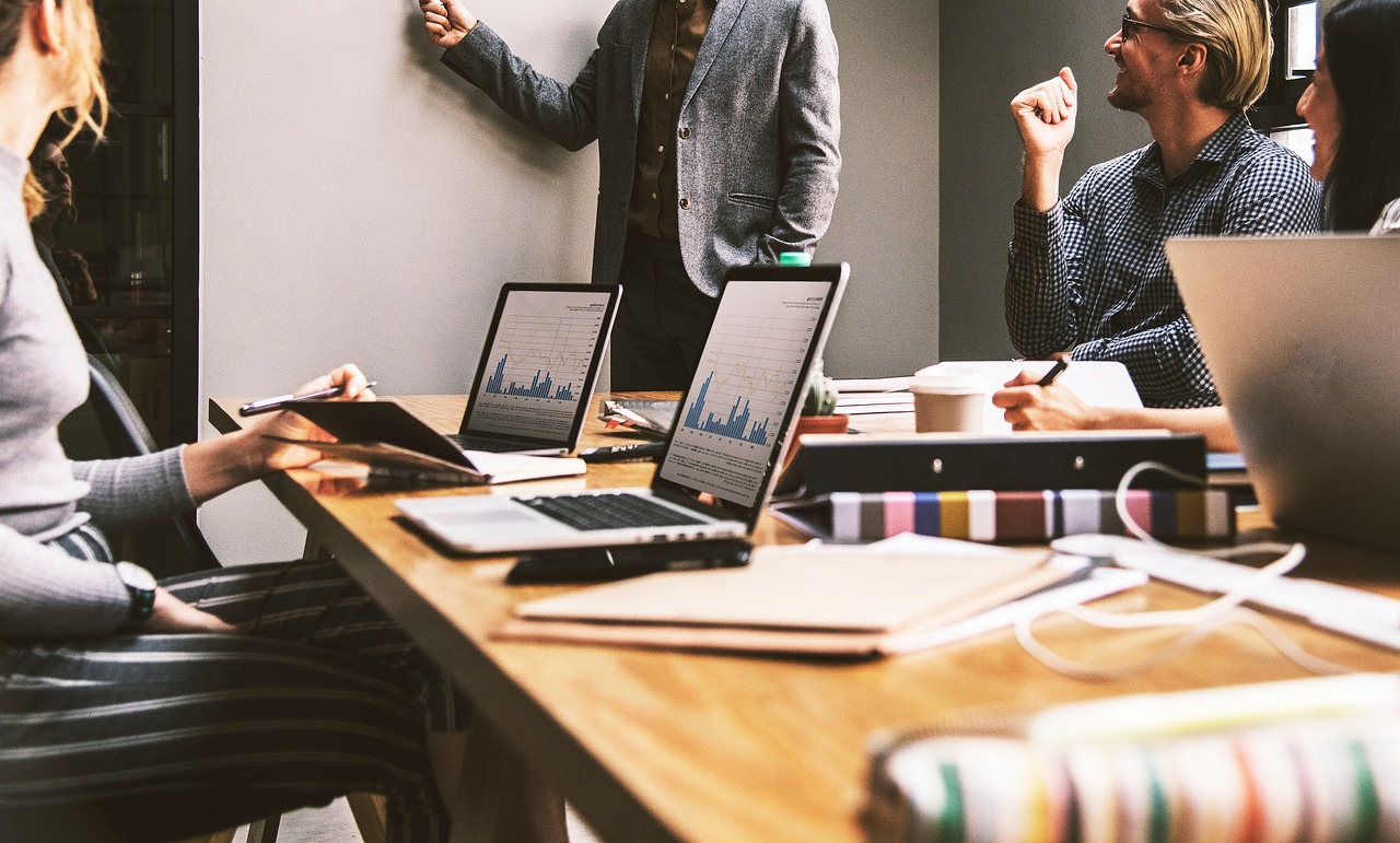 Equipo de trabajo reunido en una oficina pequeña, debatiendo ideas alrededor de una mesa
